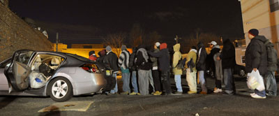 (RNS4-MAR04) Men line up for meals in a cold parking lot prepared by Miryam Torres of East Orange, N.J., who distributes food each week for illegal immigrants who live in poverty and are scared to go to soup kitchens. For use with RNS-IMMIGRANT-FEED, transmitted March 4, 2009. Religion News Service photo by Mark Dye/The Star-Ledger. 