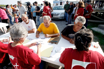 (RNS1-JUNE1) Fishermen Santos Toledo, left, Donal Melerine, center, and an unidentified fisher, right, fill out forms to receive relief packages for out-of-work fishermen distributed by Catholic Charities and the local non-profit Santa on the Bayou. For use with RNS-SPILL-PRAYERS, transmitted June 11, 2010. RNS photo by Rusty Costanza/The Times-Picayune. 