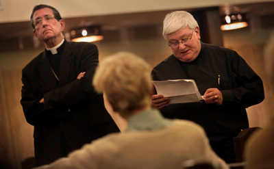 (RNS2-DEC07) Bishop Richard Lennon of Cleveland listens as the Rev. Paul Rosing reads a court injunction prohibiting protesters from occupying St. John the Baptist Church in Akron hours before the church's final Mass. For use with RNS-LENNON-PROFILE, transmitted Dec. 7, 2010. RNS photo by Gus Chan/The Plain Dealer. 