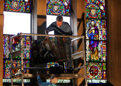 (RNS2-JAN26) Ray Clagnan hands an image of Mary Magdalene to fellow artisan Joe Henchenski as they remove the stained glass windows at the shuttered Sacred Heart Catholic Church in Newark, N.J. For use with RNS-WINDOWS-REUSE, transmitted Jan. 26, 2011. RNS photo by  John Munson/The Star-Ledger 