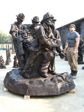 (RNS) Sculptor Timothy Schmalz stands next to scale bronze replica of his statue depicting several firefighters carrying the body of the Rev. Mychal Judge, the "9/11 saint."  Religion News Service file photo courtesy of Timothy Schmalz. 