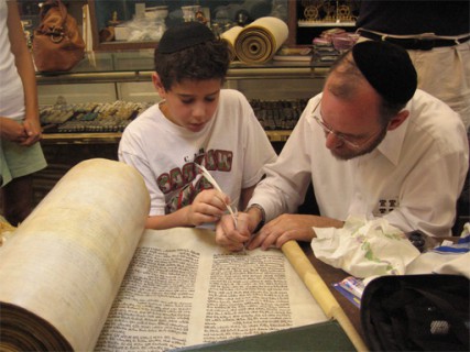 (RNS1-NOV01) In 2008, Ethan Ulanow assists Rabbi Menachem Youlus in completing the final letter of a restored scroll that Ethan and his family bought, then donated to a synagogue in Katrina-ravaged Metairie, La. Youlus was later charged with fraud for saying the scroll (and others) was rescued from the Ukraine during the Holocaust.  For use with RNS-TORAH-TALES, transmitted Nov. 1, 2011. Photo courtesy Washington Jewish Week. 