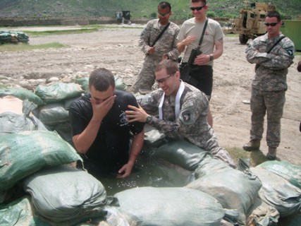 Army Chaplain Capt. Joseph Odell baptizes a fellow soldier on the field in Afghanistan. 