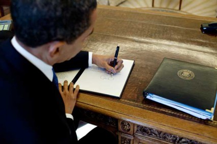 President Barack Obama writes at his desk in the Oval Office (3/3/09). 