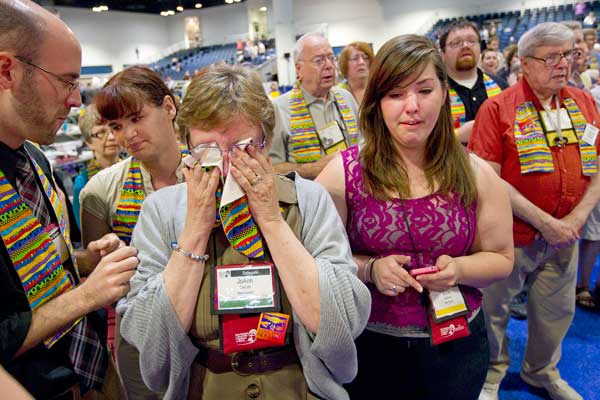 Delegate Jo Ann Carlotto (second from left) of the New England Conference wipes her eyes with a rainbow stole after delegates voted to maintain the United Methodist Church's stance on sexuality during the denomination's at 2012 General Conference in Tampa, Fla. 