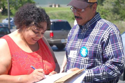 A voter signs a petition as Noah Angel, right, looks on. Rev. Angel, pastor of Familia Christiana Internacional in Jefferson City, Mo., served with clergy from across Missouri on April 18, 2012 to collect voter signatures to cap the rate on short-term loans in the state. 