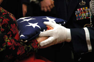 The flag that covered Raymond A. Gress' casket is handed to family members after his funeral. Gress' son, Raymond C. Gress, was able to watch the funeral over the Internet from Iraq (2007). 