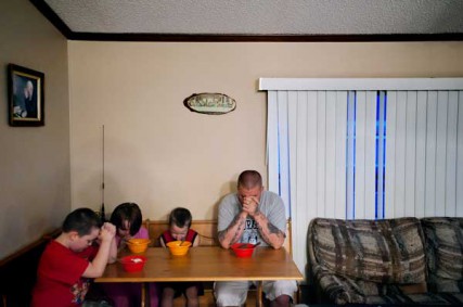 Chris Simpson, right, prays with his children, Cody, left, Kayleigh, and Nikolaus over their dessert of ice cream Monday night, April 30, at their home in Jackson. Though he was raised Methodist, Simpson and his wife, Misty, followed the Norse religion until coming back to Christianity shortly after his decision to leave the white supremacy movement. 