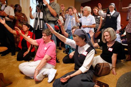 Attendees hold their hands up during a blessing by Archbishop Gregory Aymond, during the opening of the Magnificat House of Discernment for Women in New Orleans, Louisiana, Wednesday, August 15, 2012. 