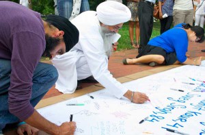Attendees sign a banner during the prayer vigil for the victims of the Oak Creek Sikh temple shooting on Wednesday evening, August 8, in Lafayette Park in view of the White House. RNS photo by Chris Lisee