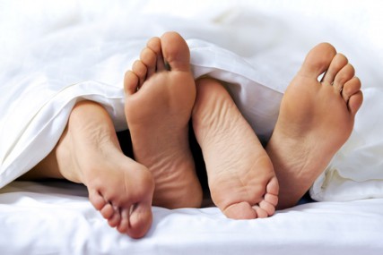 Close-up of the feet of a couple on a bed via www.shutterstock.com 