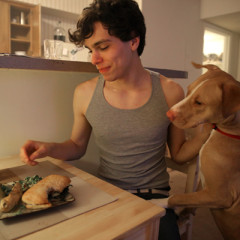 Vlad Chituc, 23, gets ready to eat his Quinoa Tabbouleh and portobello burger, much to the interest of his dog "Toad", at his apartment in Durham, N.C., Wednesday, March 13, 2013. RNS photo by Ted Richardson