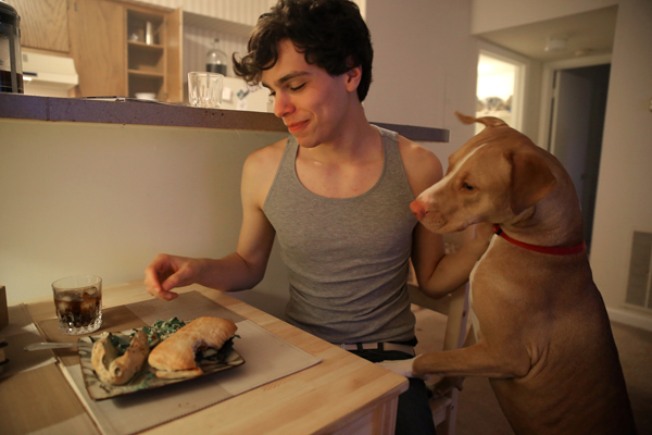 Vlad Chituc, 23, gets ready to eat his Quinoa Tabbouleh and portobello burger, much to the interest of his dog 