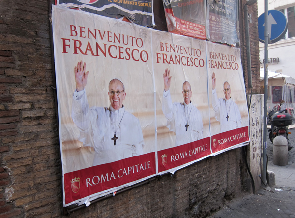 Signs line a wall in Rome welcoming Pope Frances. RNS photo by David Gibson