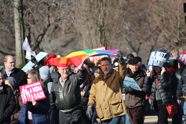 Two advocates for gay marriage join the March for Marriage as its participants head toward the Supreme Court to oppose same-sex marriage. Throngs of supporters and opponents gathered outside the high court as it considered cases about same-sex marriage. RNS photo by Adelle M. Banks