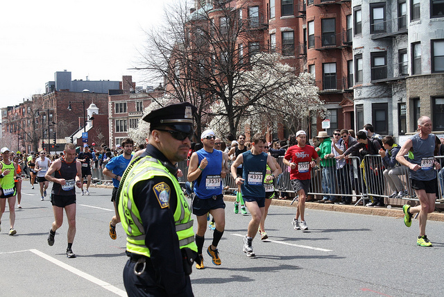 A Police officer stands by as runners pass during the 2013 Boston Marathon.  Photo courtesy Sonia Su via Flickr (http://flic.kr/p/ebzEmM)