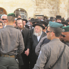 A group of men pray at the sacred Western Wall while surrounded by Israeli police. RNS photo by Michele Chabin