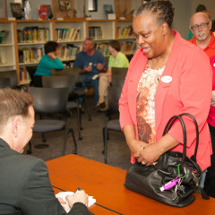 A woman gets her copy of ‘Hidden Voices: Reflections of a Gay, Catholic Priest” signed by author Gary M. Meier. Photo by Michael K. Butler Sr./UMSL
