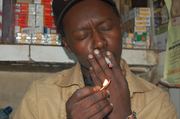 A man lights a cigarette in Nairobi, Kenya. Smoking of bhang and tobacco products are some of the substances being abused. Photo by Fredrick Nzwili