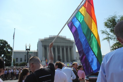 A man holds a gay pride flag in front of the Supreme Court on Wednesday (June 26, 2013) after the court decided to strike down the Defense of Marriage Act.  RNS photo by Adelle M. Banks