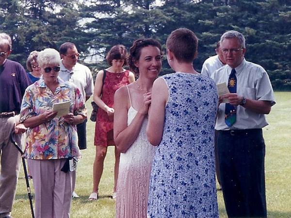 Rev. Steve Heiss, pastor at Tabernacle United Methodist Church in Binghamton, N.Y., officiates at the July 2, 2002 commitment ceremony of his daughter, Nancy Heiss (blue dress) and Kim Willow (pink and white dress) in a field in Norwich, N.Y. Photo courtesy Steve Heiss