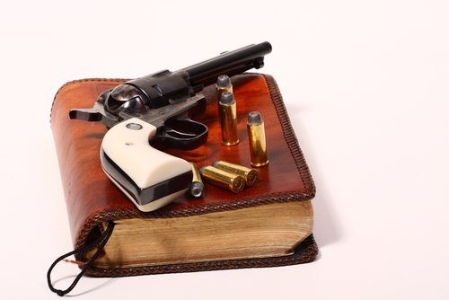 A gun and the Bible. Image courtesy of timotheos via Shutterstock