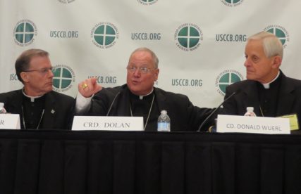New York Cardinal Timothy Dolan, center, president of the U.S. Conference of Catholic Bishops, speaks at a news briefing on the first day of the bishops' fall meeting in Baltimore on Monday (Nov. 11). Bishop John Wester, left, of Salt Lake City and Cardinal Donald Wuerl, right, of Washington, listen on. RNS photo by David Gibson 