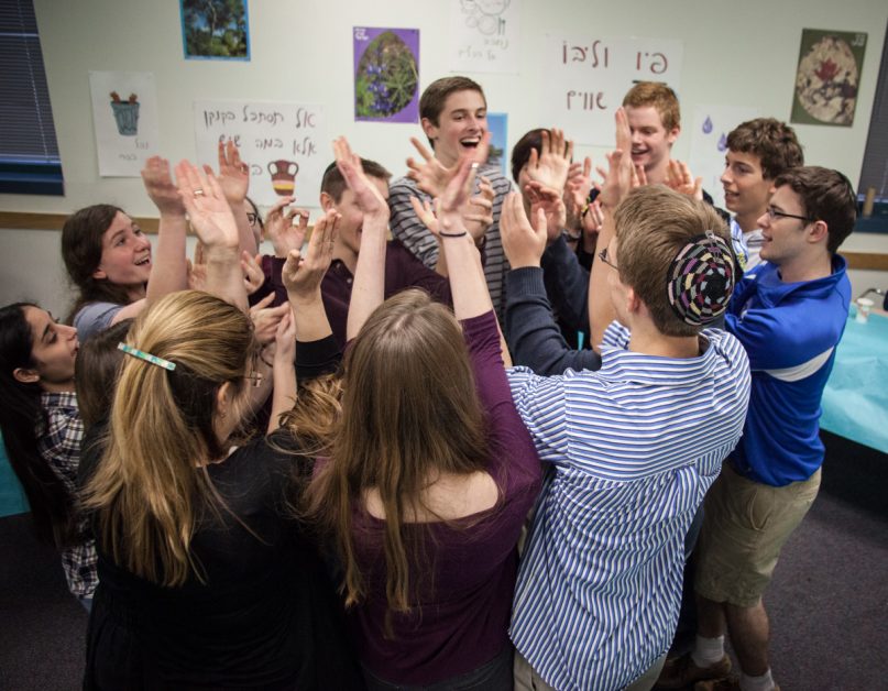 Juniors and seniors dance in a circle after a Seder to study and celebrate Tu B'Shvat during a Hebrew class at Hyman Brand Hebrew Academy in Overland Park, Kan., on Wednesday (Jan. 15, 2014). RNS photo by Sally Morrow