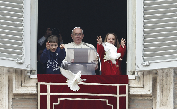 Pope Francis watches as children release doves from the window of his studio overlooking St. Peter's Square at the Vatican on Sunday (Jan. 26). The two young people at his side launched doves to highlight the church’s call for peace in the world. Photo by Paul Haring, Catholic New Service