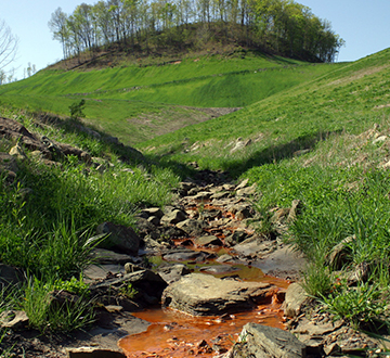 Coal companies frequently tout the benefits of reclamation and claim their practices protect and restore water quality. The red-stained water seen below this "reclaimed" mountaintop removal mine in Magoffin County, Kentucky, tells a very different story. Red water like this results from high iron levels, which in turn are an indicator of a plethora of other heavy and toxic metals like selenium, mercury and manganese. – Photo by Matt Wasson, Appalachian Voices - (http://bit.ly/1fq0SE3)