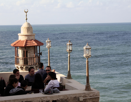 A mosque with speakers in the background of a coffee bar and restaurant in Israel.