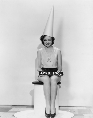 Portrait of woman with April Fool sign wearing dunce cap.