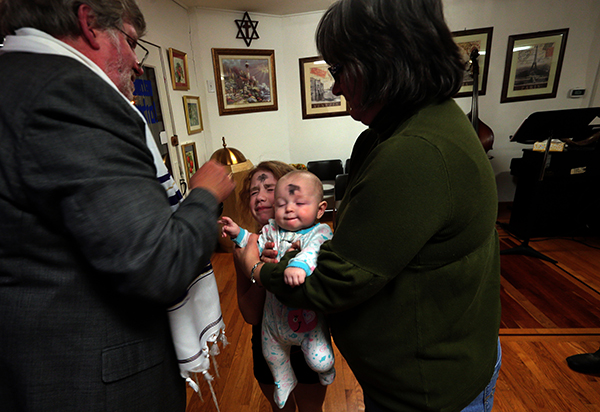 Rev. Kevin Parviz places ashes on his grandchildren Johnna Opheim, 7 1/2 and infant Aubrey Smith during Ash Wednesday service on Wednesday, March 5, at Congregation Chai v'Shalom in Dogtown with his wife Colleen, right.The service combined both Christian and Jewish liturgy. Photo by Laurie Skrivan, courtesy of St. Louis Post-Dispatch
