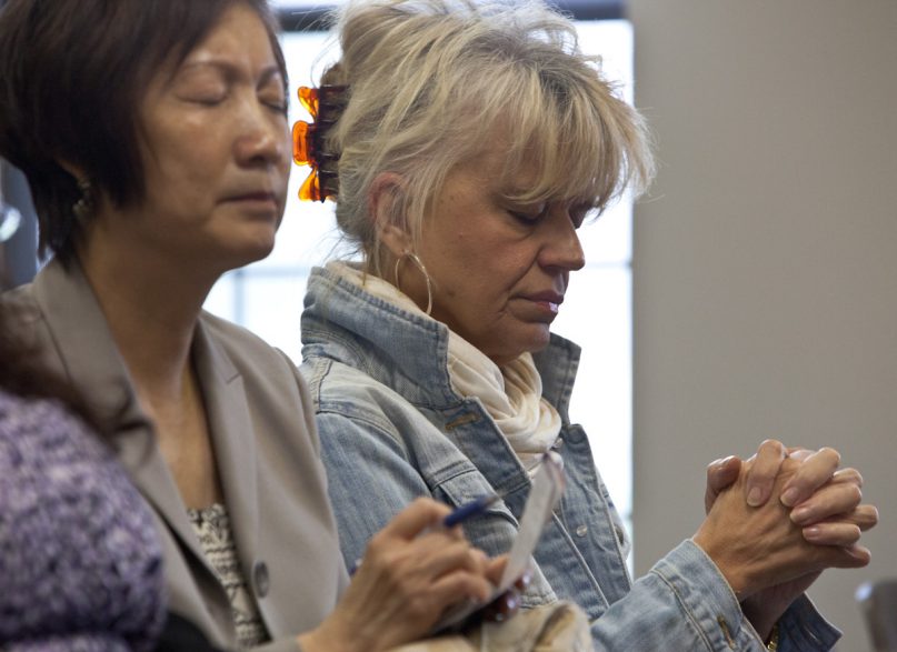 Gretchen Tveitmoe, right, from Grandview, Mo. prays alonside Alice Wong, left, during a prayer service at Lake Lotawana City Hall in Lake Lotawana, Mo., on National Day of Prayer, May 1, 2014. Religion News Service file photo by Sally Morrow
