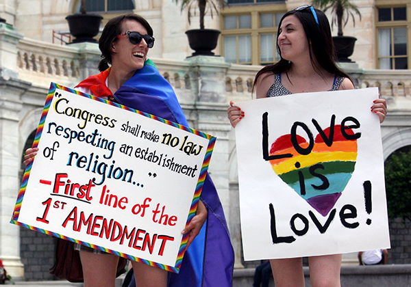 Mandy Roach, left, and Amy Joslin stood behind the March for Marriage speakers and raised signs supporting marriage equality on June 19 in Washington, D.C. Religion News Service photo by Heather Adams