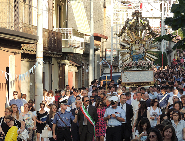 Oppido Mamertina Mayor Domenico Giannetta, center, flanked at left by Italian Carabinieri officer Andrea Marino, walks during a religious procession in Oppido Mamertina in southern Italy's Calabria region. In apparent defiance of Pope Francis, the church procession detoured from its route to honor a convicted mobster under house arrest.