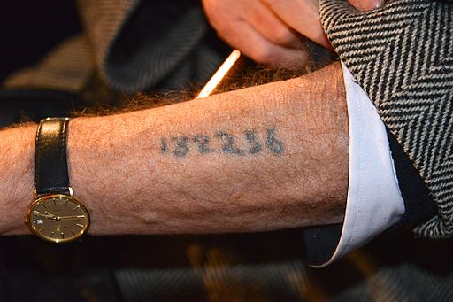 A survivor shows his tattoo during a memorial ceremony at the Raoul Wallenberg square in Stockholm with Holocaust survivors.
