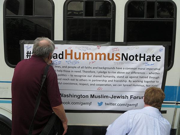 Sympathizers sign the "Spread Hummus Not Hate" banner on a bus parked at Farragut Square in Washington, D.C. Tuesday (Oct. 16), part of a campaign by the Greater Washington Muslim-Jewish Forum, a group of Muslims and Jews that formed earlier this year to combat Islamophobia and anti-Semitism. The group's one-day bus tour took it to six stops including the University of Maryland, a D.C. mosque and a private home in Virginia. Religion News Service photo by Lauren Markoe
