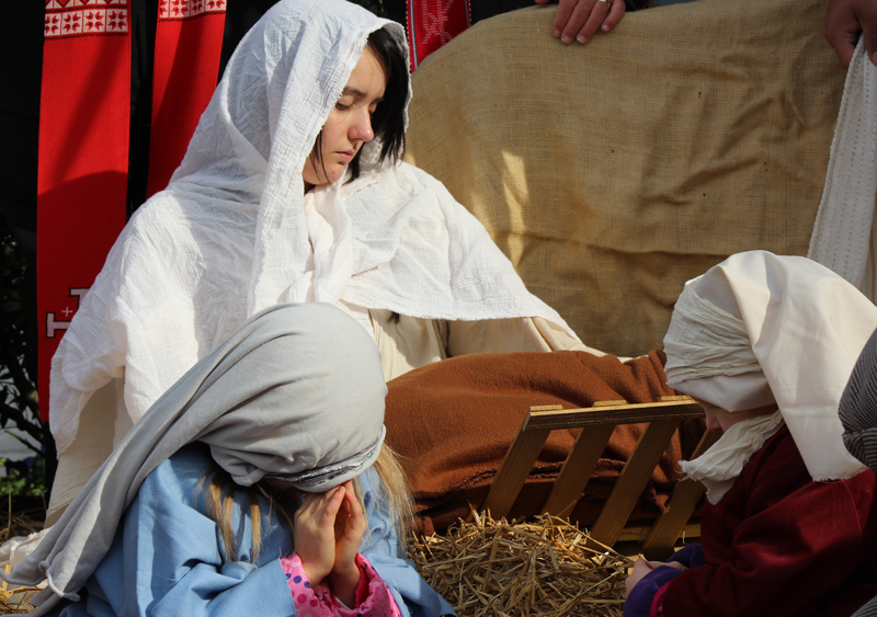 Gwen Weast of Manassas, Va., prays next to her swaddled baby Kimberly as they play Mary and baby Jesus in the Live Nativity of the Faith and Action ministry in Washington, D.C., on December 11, 2014. Layla Sowers, left, and Briella DeLeon, right, join in the prayer. Religion News Service photo by Adelle M. Banks
