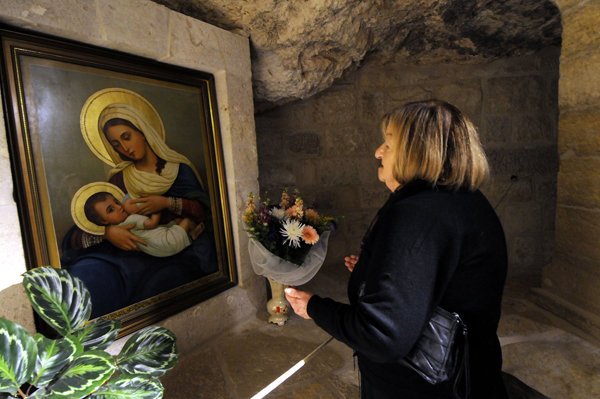 Hilda Berkley of Bethlehem, West Bank, prays at a painting of Mary breast-feeding the infant Jesus at the Milk Grotto chapel in Bethlehem. The Milk Grotto is believed to be where Mary breast-fed the baby Jesus. RNS photo courtesy Debbie Hill/Catholic News Service.