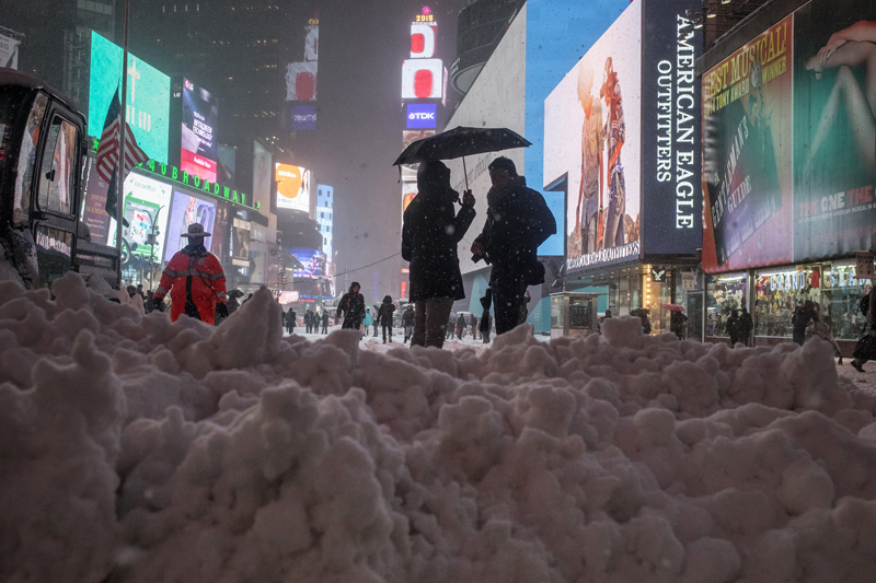 Commuters stand under an umbrella next to snow which was being plowed to the street edge from a walkway in Times Square, New York on January 26, 2015. A massive blizzard slammed into the U.S. Northeast on Monday, canceling thousands of flights, curtailing mass transit and closing hundreds of schools, as officials warned that the storm could dump as much as 3 feet of snow on the region. Photo courtesy of REUTERS/Adrees Latif 
*Note: This photo may only be republished with RNS-EHRICH-COLUMN, originally published on January 27, 2015