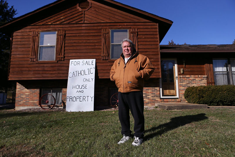 Mike Stenzhorn, 62, stands on his front lawn in Dittmer on Wednesday (Dec. 17, 2014). He lives directly across the street from the Vianney Renewal Center, a Roman Catholic institution for pedophile priests. He claims the archdiocese won't offer him a fair price for his house, though they bought each of his neighbors' houses for close to double the market value. He's afraid due to his pedophile neighbors, he won't be able to sell the house to anyone else. Stenzhorn said he posted the sign in front of his house, 