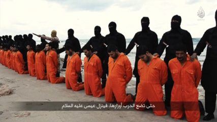 Men in orange jumpsuits purported to be Egyptian Christians held captive by the Islamic State (IS) kneel in front of armed men along a beach said to be near Tripoli, in this still image from an undated video made available on social media on February 15, 2015. Photo courtesy of REUTERS/Social media via Reuters TV *Editors: This photo is not available for republication.