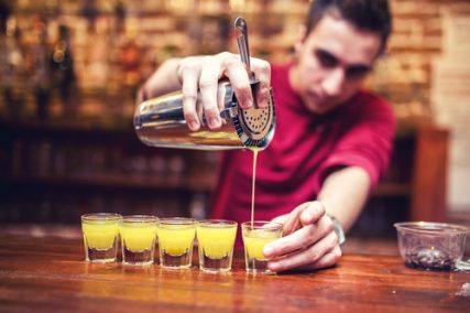 A bartender pours shots.