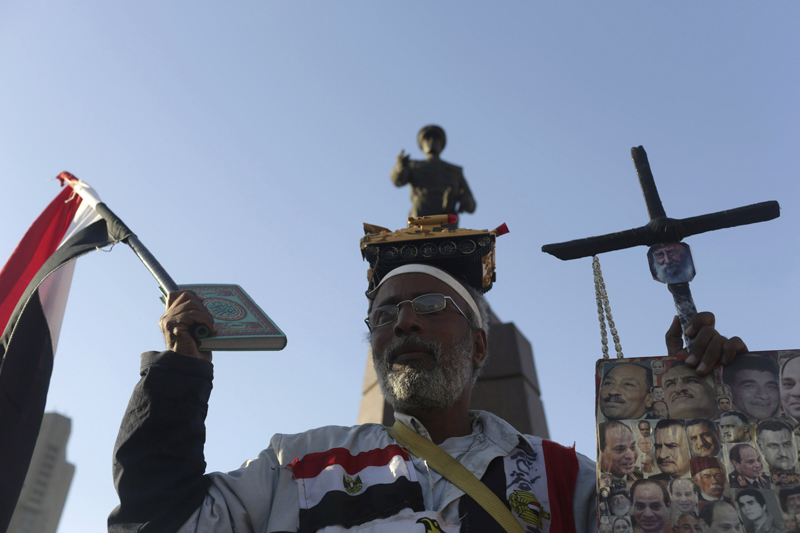  A supporter of Egypt's former army chief Field Marshal Abdel Fattah al-Sisi holds a Koran, a cross and flags as he celebrates the announcement of his candidacy for presidential election in Tahrir square in Cairo on March 28, 2014. Photo courtesy of REUTERS/Asmaa Waguih
*Editors: This photo can only be republished with RNS-EGYPT-ATHEIST, originally transmitted on February 2, 2015.