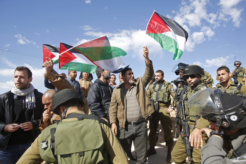 Protesters hold Palestinian flags as they stand next to Israeli soldiers and border policemen during a protest against Jewish settlements in Jabaa, south of the West Bank city of Bethlehem on February 7, 2015. Photo courtesy of REUTERS/Mussa Qawasma 
*Editors: This photo may only be republished with RNS-MOSQUE-ARSON, originally transmitted on February 25, 2015.