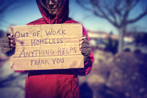 A homeless person holding a sign.