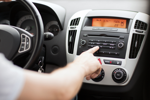 A driver changes the car radio station.