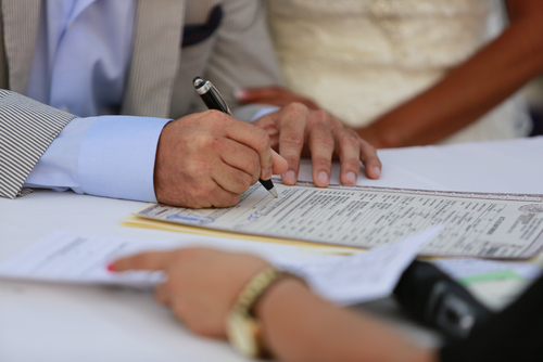 A groom signs a marriage license.