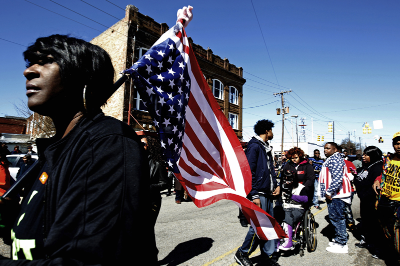 A woman walks along downtown carrying an American flag as she waits for the arrival of U.S. President Barack Obama in Selma, Ala., on March 7, 2015. With a nod to ongoing U.S. racial tension and attempts to limit voting rights, Obama declared the work of the Civil Rights Movement advanced but unfinished on Saturday during a visit to the Alabama bridge that spawned a landmark voting law. Photo courtesy of REUTERS/Tami Chappell  
*Editors: This photo can only be republished with RNS-SELMA-POVERTY, originally transmitted on March 9, 2015.